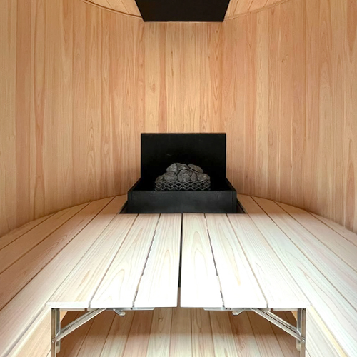 静岡県の個人宅に納品した縦型バレルサウナ BARREL SAUNA Upright。無機質なモルタル仕上げの外装に対し、内側は360度に木目が広がる総ヒノキ造りで6kWヒーターを搭載
