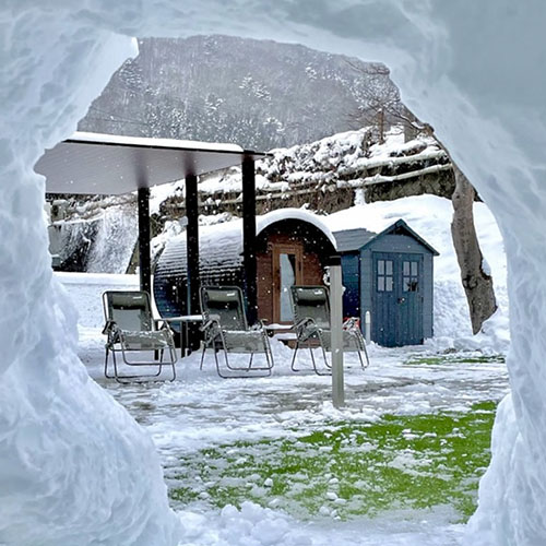 栃木県那須塩原の貸切宿「さうなす」に導入されたバレルサウナ BURROW3。雪に覆われた外気浴スペースと外気浴用のチェアが並ぶ